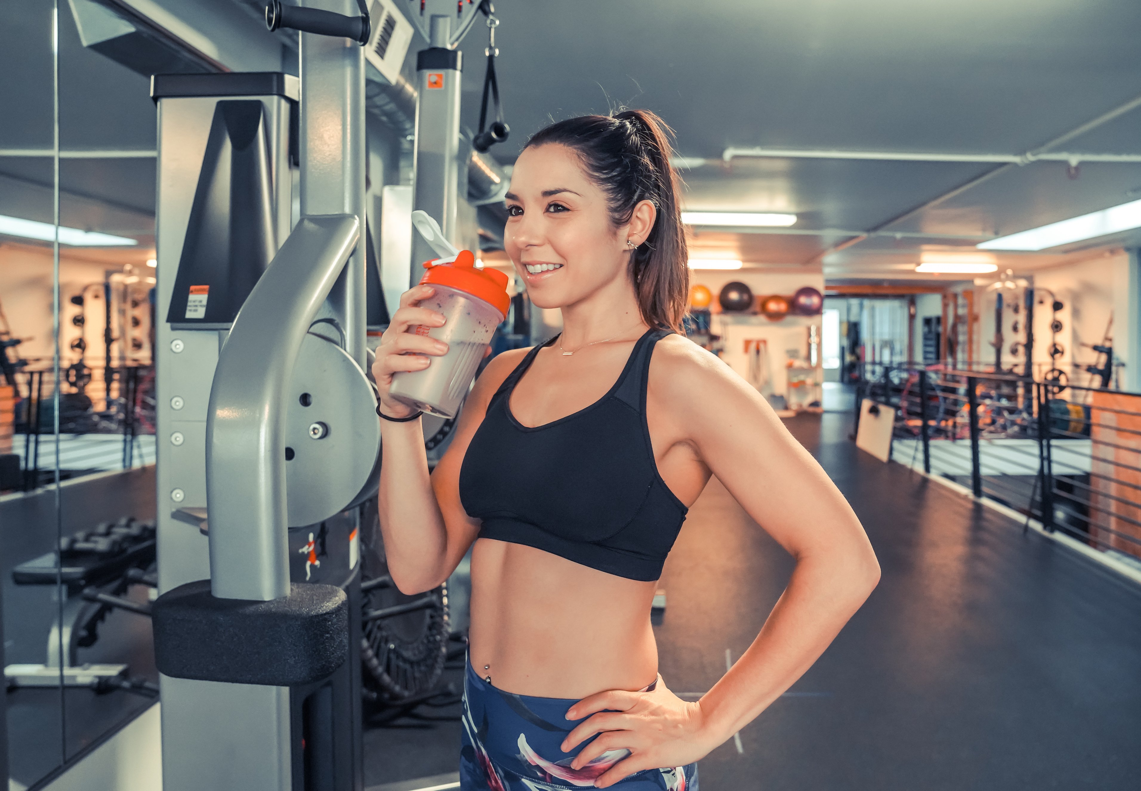 Attractive young woman drinking protein shake at gym